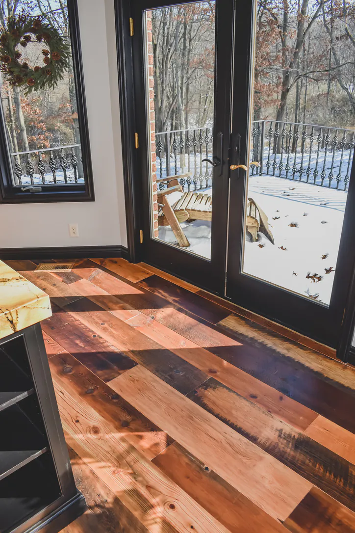 Antique barnwood flooring flowing through French doors in Brighton Michigan home