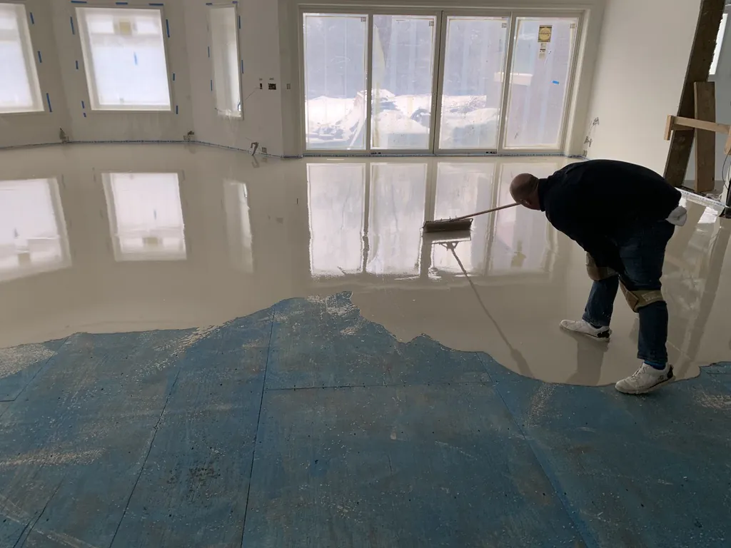 1 Wood Floors  Ed Malaski of 1 Wood Floors using a specialized needle roller to perfectly distribute and release trapped air from self-leveling underlayment (SLU) over a primed subfloor in Northville, Michigan. Installed by 1 Wood Floors, Livonia, MI